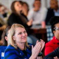 Photo of event audience clapping for speaking on stage